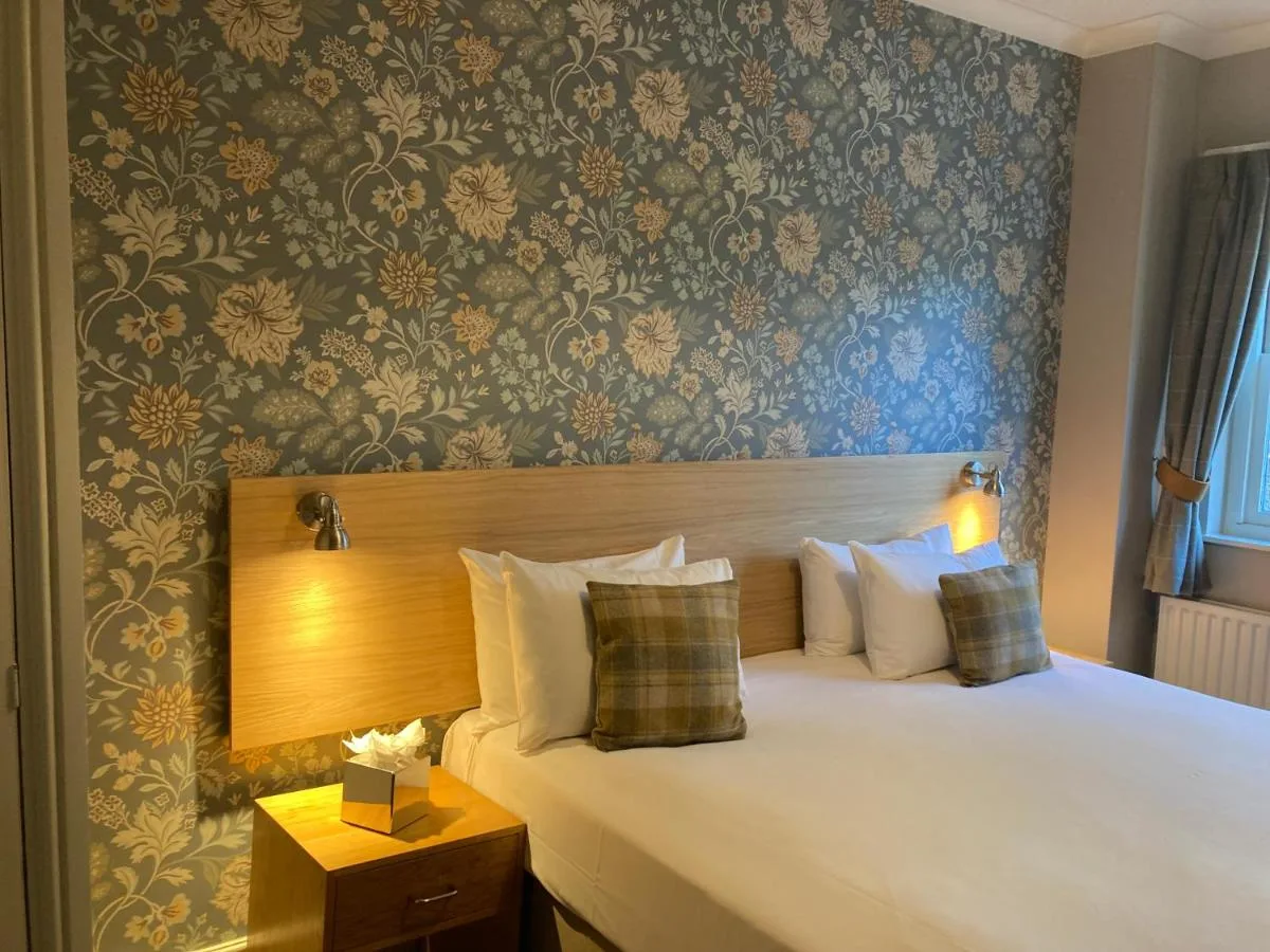 a bedroom with a bed and a wall with floral wallpaper at The Oxnoble in Manchester