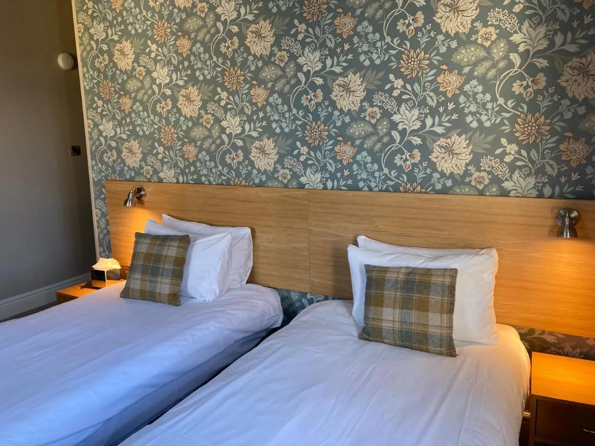 two twin beds in a hotel room with a wallpaper at The Oxnoble in Manchester
