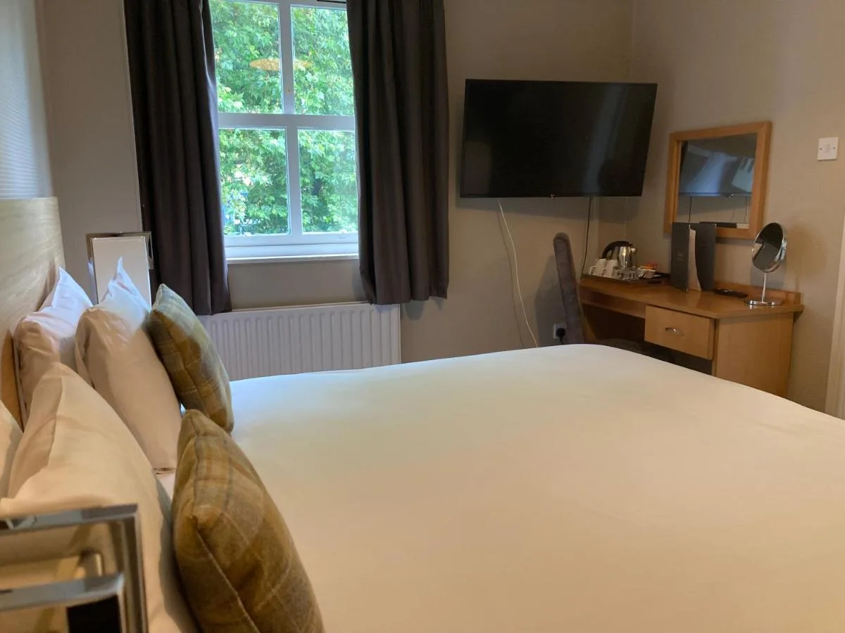 a bedroom with a large white bed with a television at The Oxnoble in Manchester