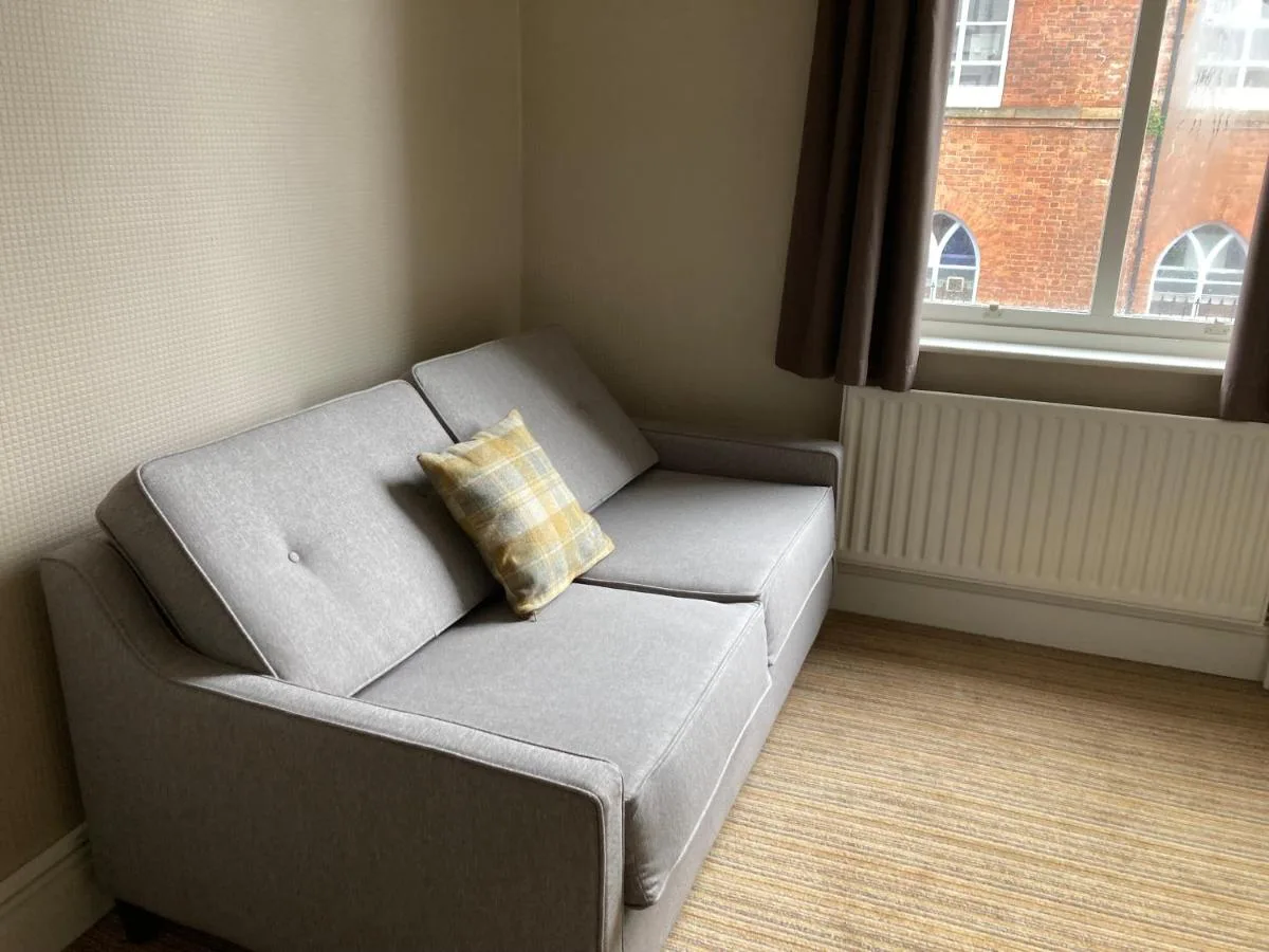a gray couch with a pillow in a room with a window at The Oxnoble in Manchester